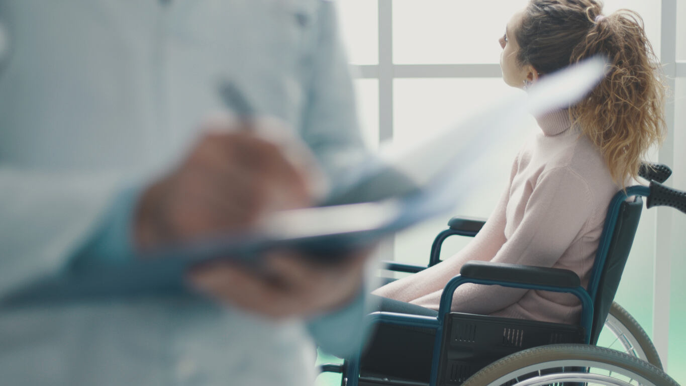 Spinal cord injured patient in a wheelchair and doctor writing