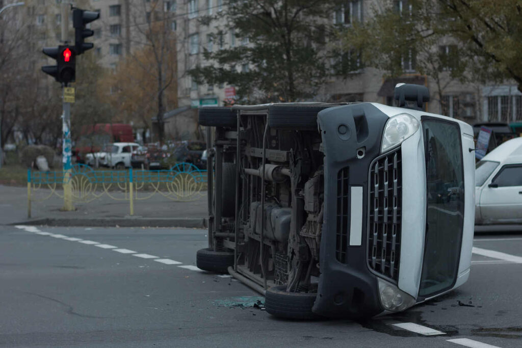 An overturned car at an intersection with a red light, representing the aftermath of a serious crash involving a trucking company.